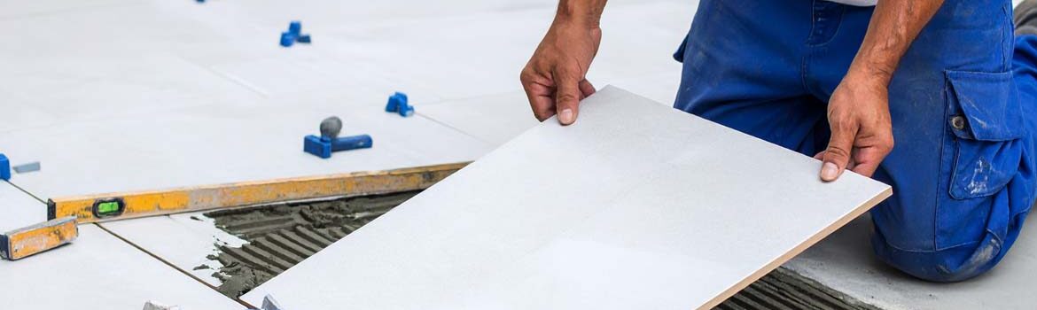 Un carreleur professionnel appliquant du mortier-colle et posant un carreau avec les "outils essentiels du carreleur", assurant une finition impeccable.