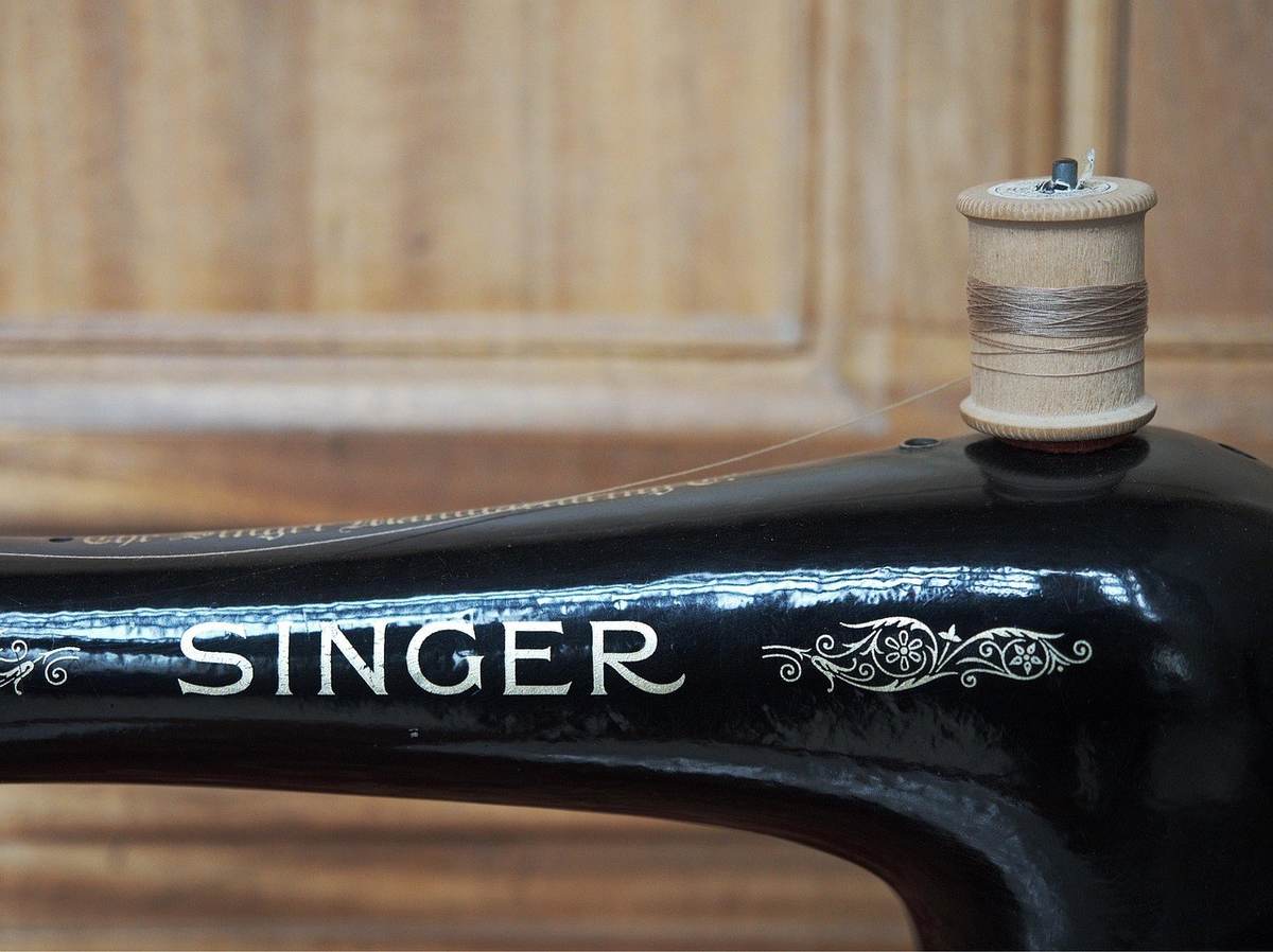 Machine à coudre Singer noire avec fil et bobine sur fond en bois Machine à coudre Singer noire avec fil et bobine sur fond en bois