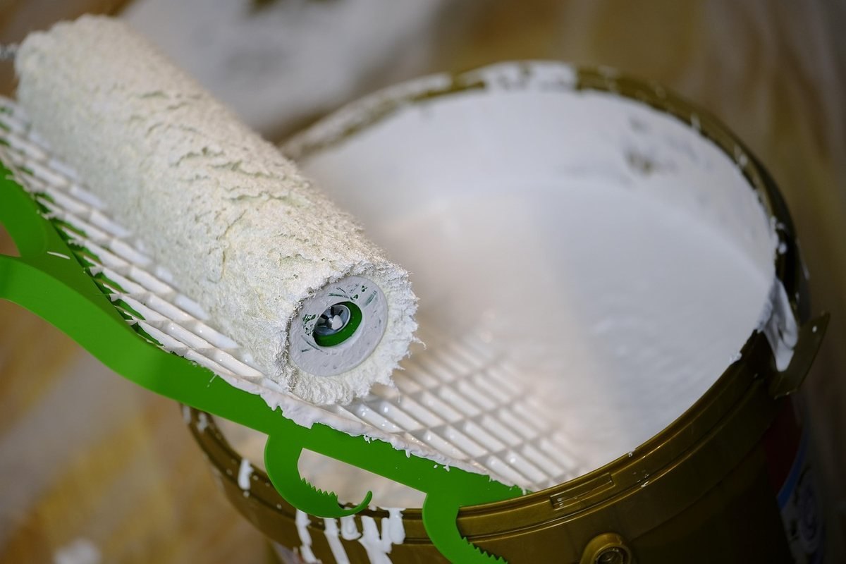 Bocal ouvert avec peinture blanche, rouleau posé dessus, manche verte
