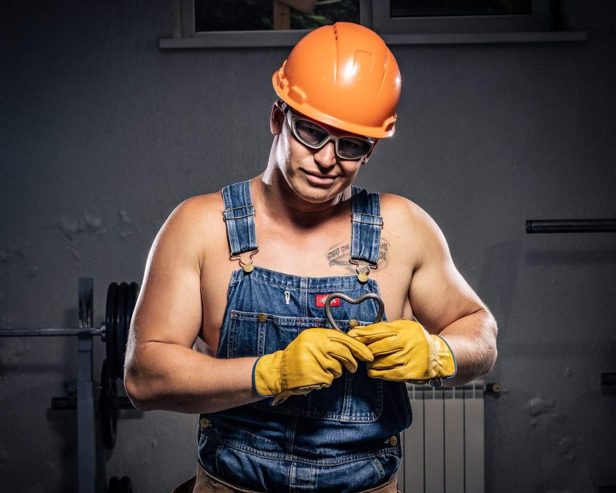 Homme en tenue de travail avec casque et lunettes, manipulant un objet dans une salle de sport