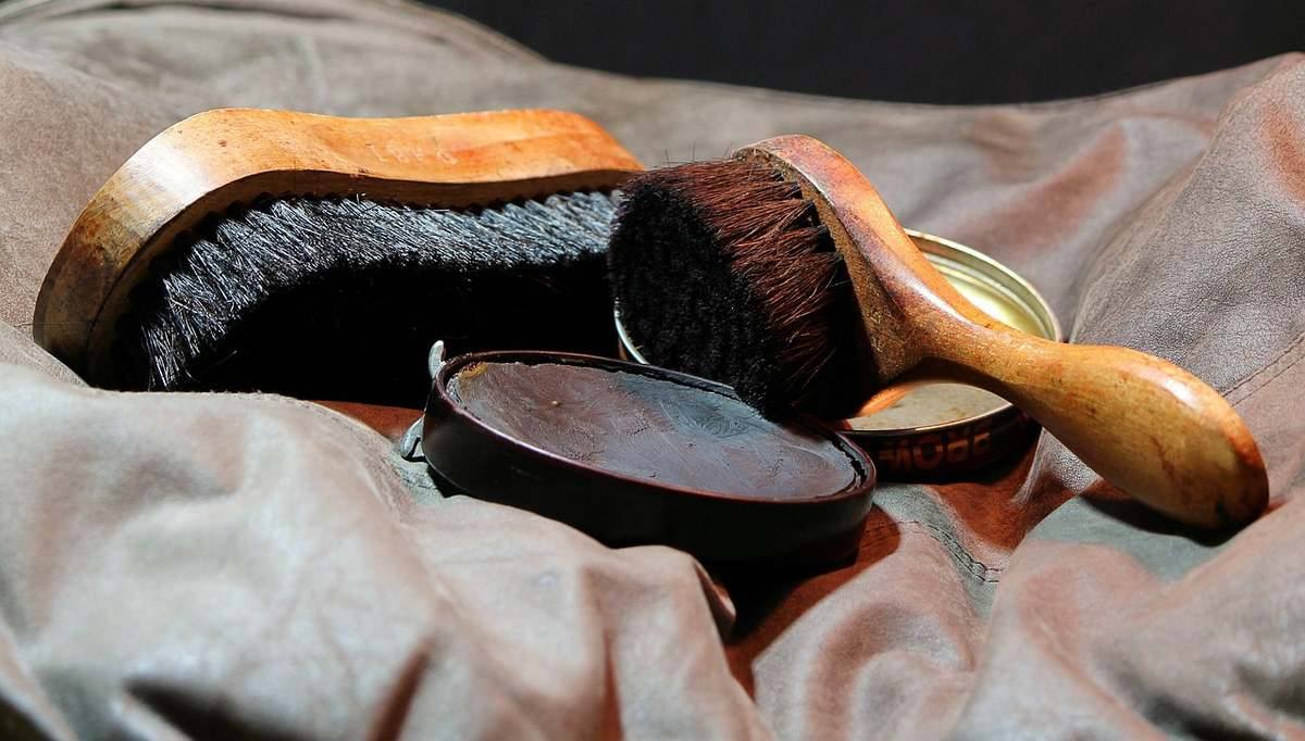 Deux brosses à cheveux en bois, une brosse à raser et un miroir sur un tissu gris