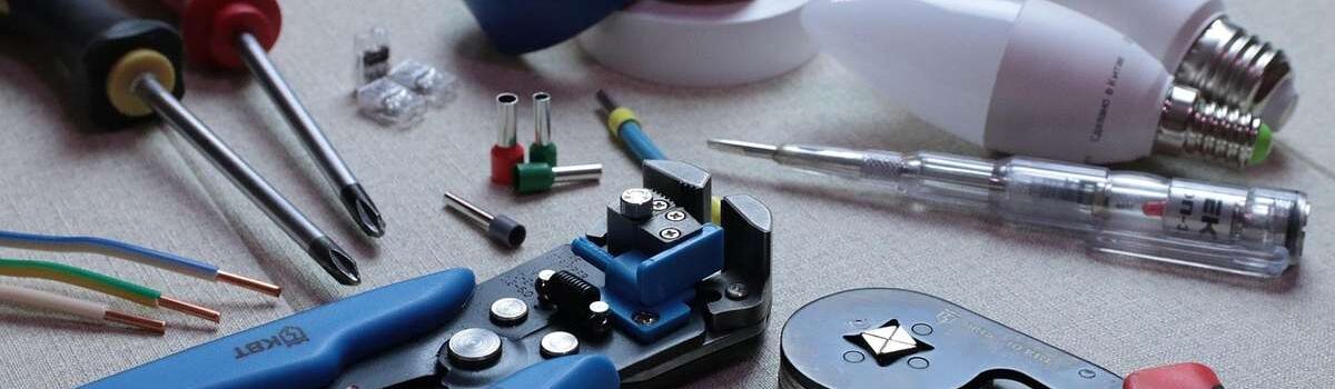 Outils de bricolage sur une table, y compris des pinces, des ciseaux, des ampoules et des fils électriques