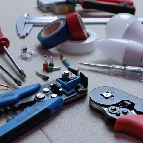Outils de bricolage sur une table, y compris des pinces, des ciseaux, des ampoules et des fils électriques