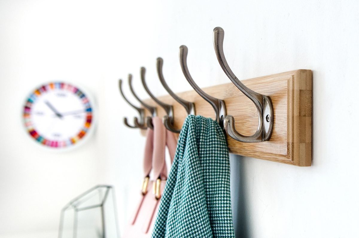 Un porte-manteau en bois accroche une serviette verte et une écharpe rose