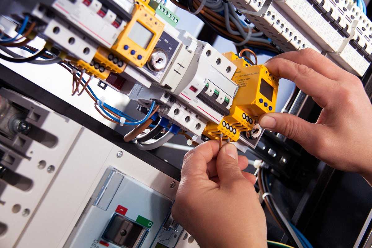 Technicien ajuste un disjoncteur dans un tableau électrique complexe