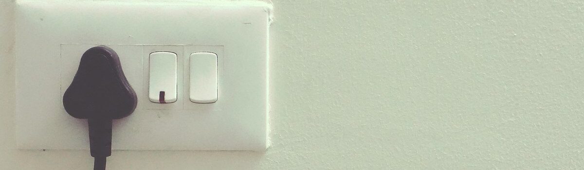 Mur blanc avec prise, deux interrupteurs et fiche noire