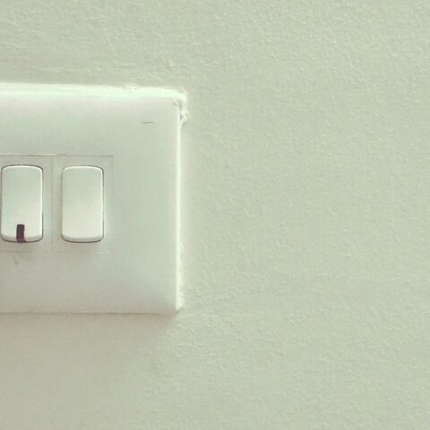 Mur blanc avec prise, deux interrupteurs et fiche noire