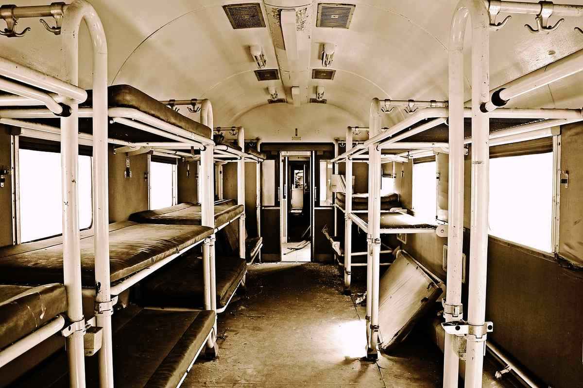 Intérieur d'une voiture de train de nuit avec couchettes superposées le long des parois et colonnes de support blanches