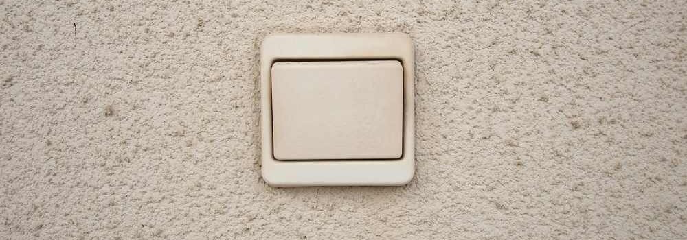 Un interrupteur lumineux blanc sur un mur texturé
