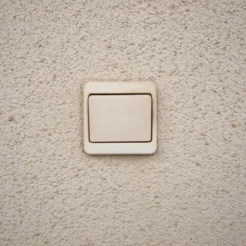 Un interrupteur lumineux blanc sur un mur texturé