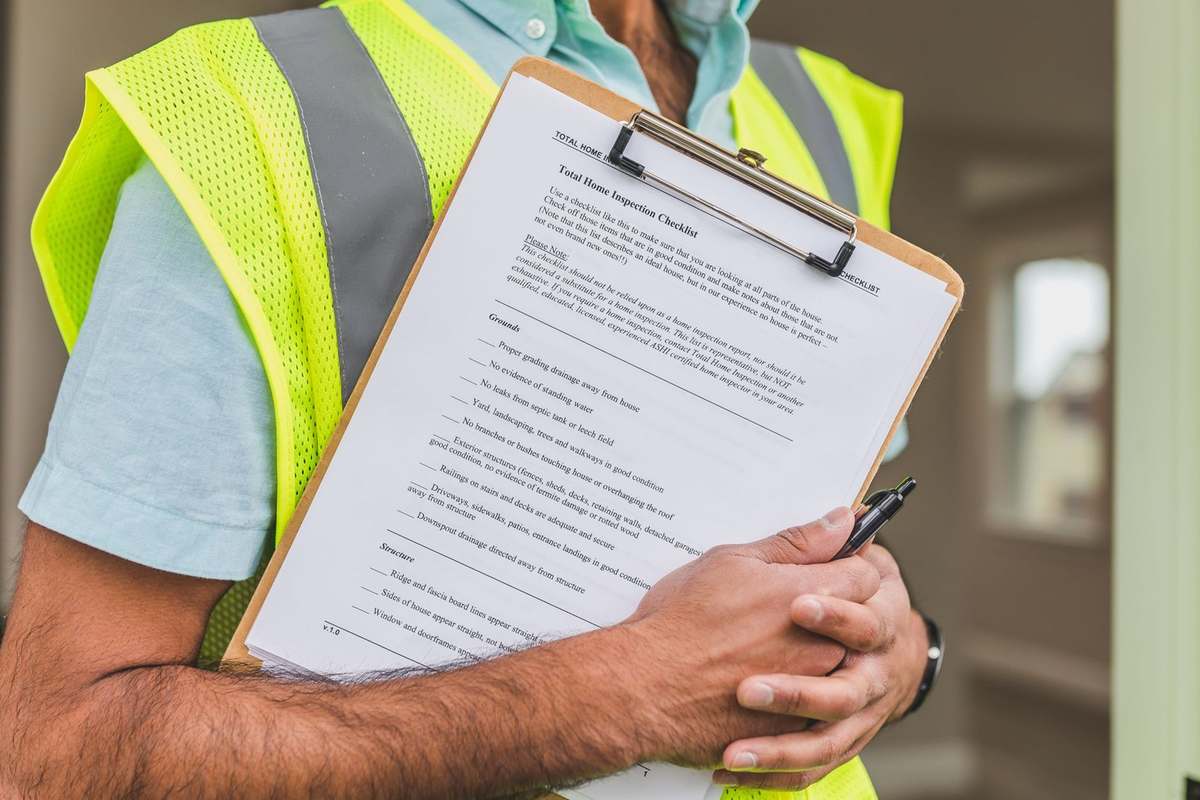 Inspecteur tenant un clipboard avec un document, gilet fluorescent, intérieur flou